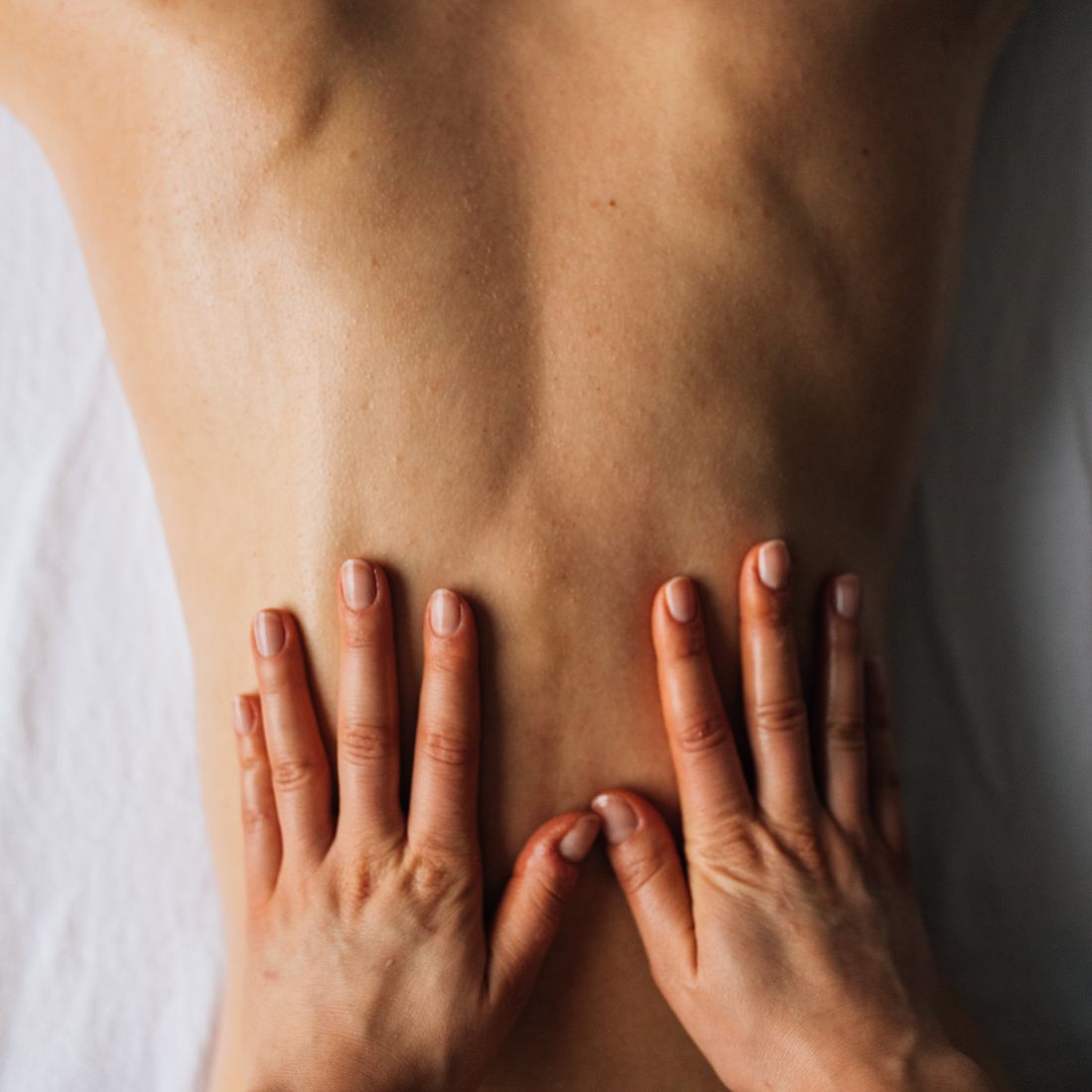Detalle: las manos de la terapeuta trabajando la espalda